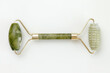 Facial jade massage roller made of green quartz stone on white background.