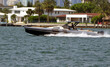 High-end motorboat powered by three outboard engines racing past luxury home on Dilido Island off`Miami Beach.