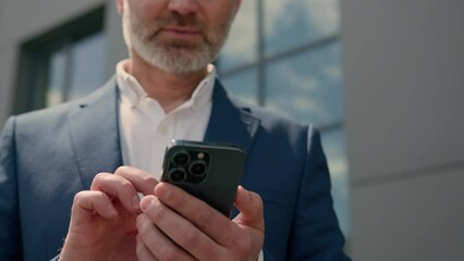 Middle-aged man senior mature business employer businessman browsing mobile phone chatting app smartphone check email network media scrolling cellphone in city near office building smiling at camera
