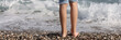 Children feet barefoot on pebble beach near sea