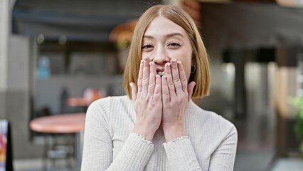 Sticker - Young blonde woman standing with surprise expression at coffee shop terrace