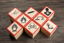 Wooden Blocks Showing Different Symbols Of Chemical Hazard Warnings On Wood Table. Illustration Of The Concept Of Toxic Substances And Occupational Health
