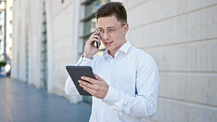 Poster - Young hispanic man talking on smartphone using touchpad at street