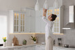 Woman changing lightbulb in ceiling lamp at home