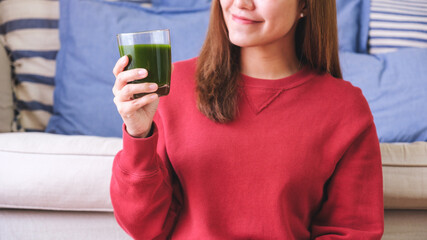 Wall Mural - Closeup image of a young woman drinking kale smoothies