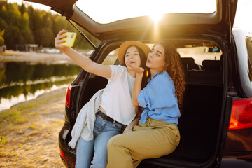 Wall Mural - Two Young woman takes a selfie in the car during a road trip. Lifestyle, travel, tourism, nature, active life.