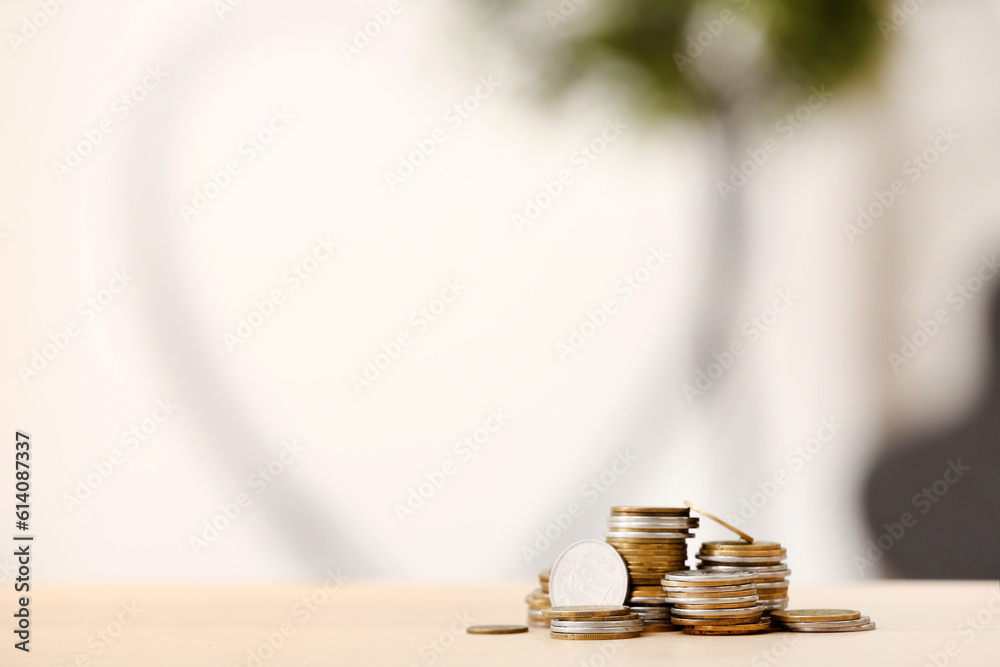 Stacks of coins on wooden table against blurred background