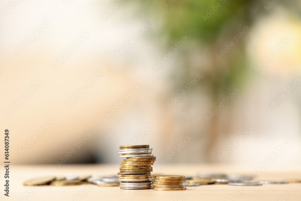 Stacks of coins on wooden table against blurred background