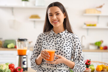 Young woman with glass of vegetable juice in kitchen