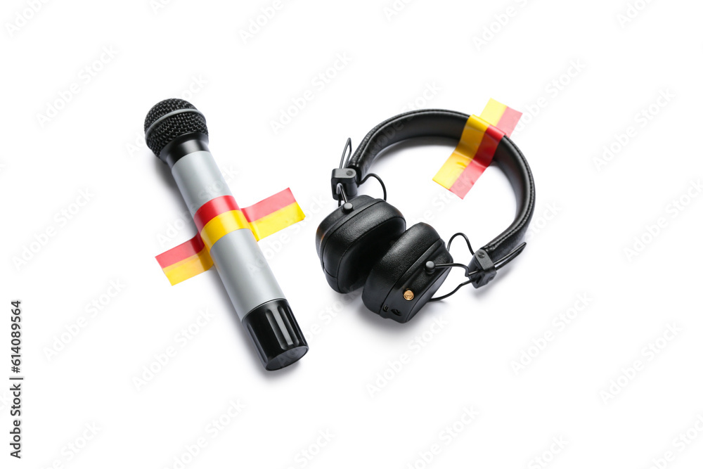 Microphone with headphones and adhesive tapes on white background