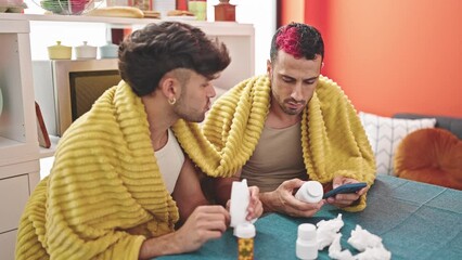 Canvas Print - Two men couple consulting medical information by smartphone at dinning room