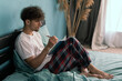© Andrii Lysenko - Handsome young man taking notes in notebook while lying on bed writing down ideas and doing planning