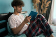 © Andrii Lysenko - Man in pajamas sitting on his bed writing notes in journal