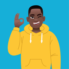 Wall Mural - African successful confident boy in yellow hoodie shows ok sign gesture. Happy black young guy with glasses.