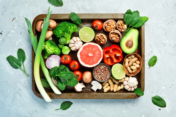 Wall Mural - Fresh tasty ingredients for healthy cooking or salad preparation on a rustic background, top view, banner: Fresh Vegetables, Nuts and Fruits. On a stone background. Top view. Copy space.