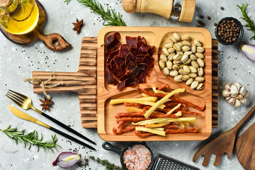 Wall Mural - Snacks for beer. Pistachios, cheese, sausages and dried meat. On a wooden plate. Rustic style.