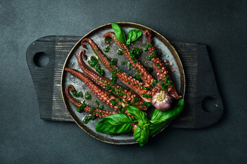Wall Mural - Close up of delicious octopus tentacles with basil and garlic. On a black stone plate. Seafood.