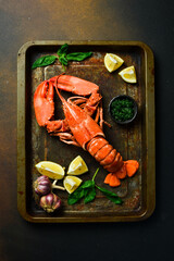 Wall Mural - grilled lobster with lemon on a black slate board. on a dark wooden table