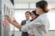 © wichayada - Casual creative happy two smile asian business people plan strategy analysis and brainstorm putting post it sticker note to share idea for startup project on white board at modern office