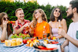 © maxbelchenko - Group of friends having fun while  drinking beer, jiking, talking at picnic party outside city on warm summer day. Joyful friendly activity for weekend.