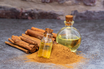 Wall Mural - Essential cinnamon oil in a small bottle, ground cinnamon and cinnamon sticks on old wooden background, selective focus