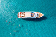Close-up overhead view of a yacht anchored in the turquoise sea and swimming tourists
