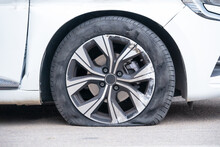 Close-up Of Flat Right Front Wheel Of Car Standing On Road With Alloy Disc. Forced Emergency Stop On The Side Of Roadside, Burst Tire, Insured Event. Broken Car Waiting Tire Shop, Tire Repair Service