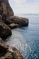 Wall Mural - Vacation. Young woman swimming and bathing at sea rock lagoon.