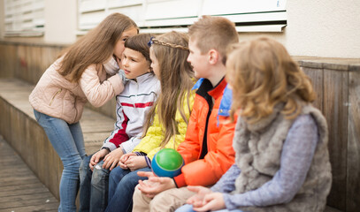 Children on a bench playing Chinese whispers