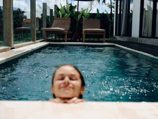 Poster - Portrait of a woman with closed eyes smile with teeth floats in the water in the pool in a swimsuit, summer vacation, vacation and travel to the tropics, beach lifestyle