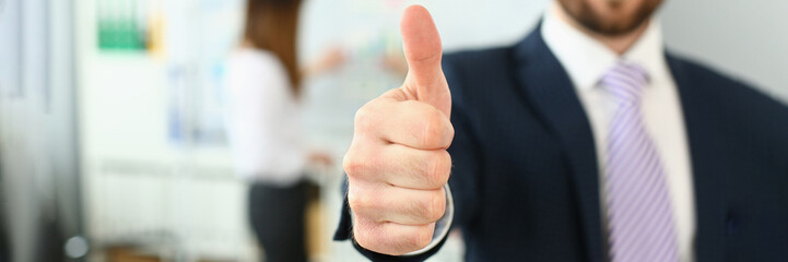 businessman showing thumb up sign of success over blurred team of business people. business consulta