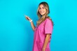 © Roquillo - Profile photo of Young beautiful doctor woman wearing pink scrubs over blue background indicate finger empty space offer