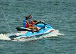 Two young women riding tandem on a jetski.