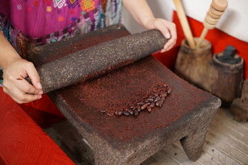 Guatemalan mayan woman making chocolate with traditional grinding stone