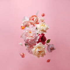 Beautiful spring flowers flying in the air, against pink background; Creative spring floral layout. Minimal birthday, valentines or wedding concept. AI generated