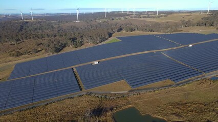 Wall Mural - aerial drone pullback reverse view of a hybrid wind and solar farm for renewable clean energy supply