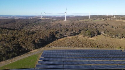 Wall Mural - aerial drone pullback reverse view of a hybrid wind and solar farm for renewable clean energy supply