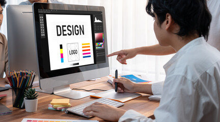 Poster - Graphic designer work on computer laptop and with graphic drawing pen while brainstorming unique design with professional graphic team in modern digital studio workplace. Panorama shot. Scrutinize