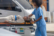 A nurse uses stretcher to carry an elderly patient to ambulance van.