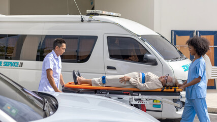 Wall Mural - Two paramedic rescuers helping a patient after having an accident. African nurse works with her colleague using stretcher to move a patient to ambulance van.