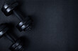 Top view of black dumbbells weights on textured mat background. Flat lay. Fitness or bodybuilding sport training concept. Copy space.
