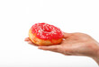 Woman hand holds red donut over white