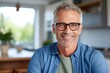 © Adriana - smiling Middle-aged guy with eyeglasses and blue shirt at home