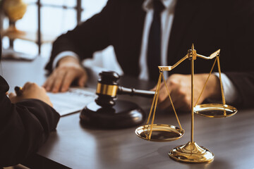 Wall Mural - Focus shiny golden balanced scale on blurred background of lawyer colleagues working on desk at law firm office. Scale balance for righteous and equality judgment by lawmaker and attorney. Equilibrium