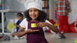 Little African-American girl in chef hat playing in kindergarten