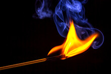 Flashed And Burning Wooden Match On A Dark Background Close-up. Bright Fire And Smoke From A Burning Tree.