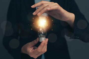 A glowing light bulb in one's hand. People search for new ideas and ideas in work and education.