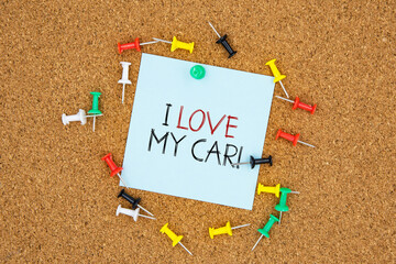 Poster - I love my car text on light blue post-it paper pinned on bulletin cork board surrounding by multi color pins. This message can be used in business concept about I love my car.