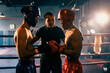 Boxer fighter with safety helmet or head guard face off with each other while referee explain rules of engage to competitor before start boxing match on the ring. Impetus