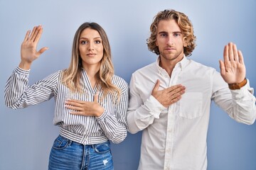 Sticker - Young couple standing over blue background swearing with hand on chest and open palm, making a loyalty promise oath